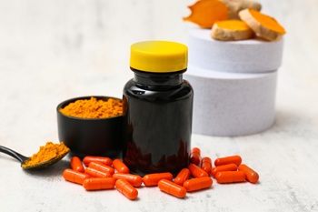 Turmeric pills and powder on white background.
